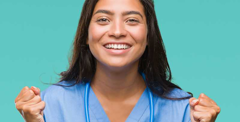 Smiling nurse in blue scrubs with a stethoscope, raising fists in celebration against a teal background.