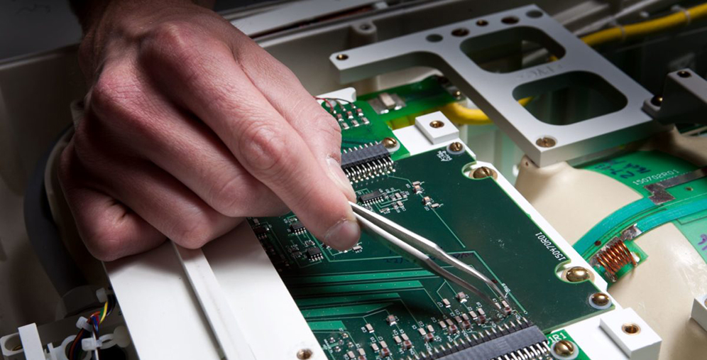 Technician uses tweezers to adjust a circuit board inside an electronic device