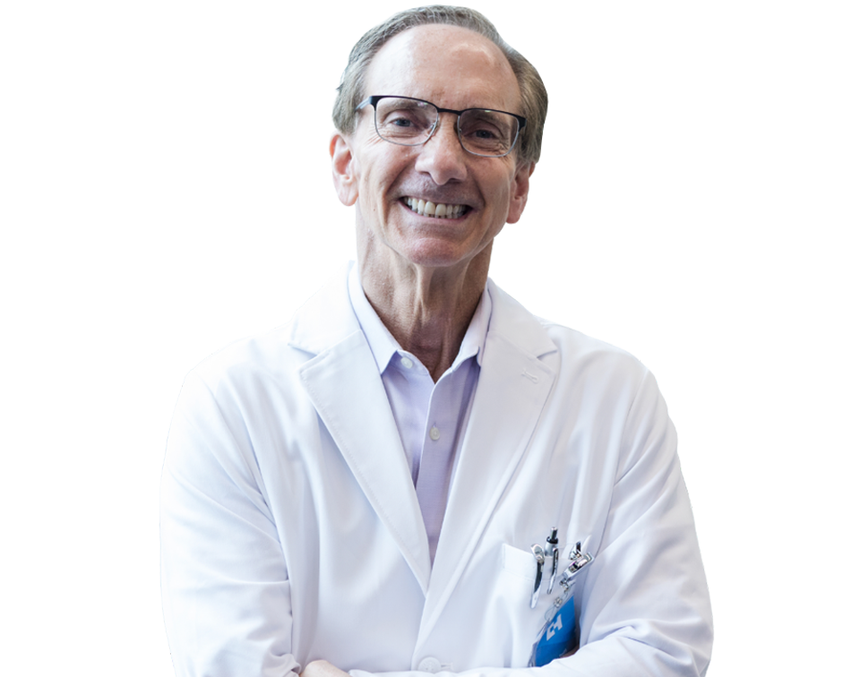 Smiling male doctor in a white lab coat with pens in the pocket, facing the camera in a portrait.