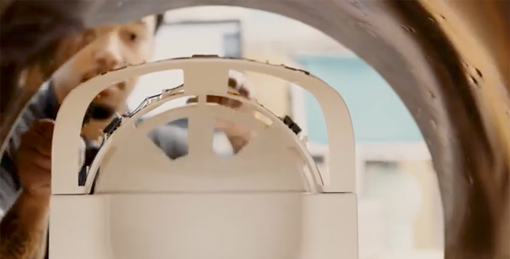Close-up of a technician assembling a white circular lab device, seen through its curved inner frame.