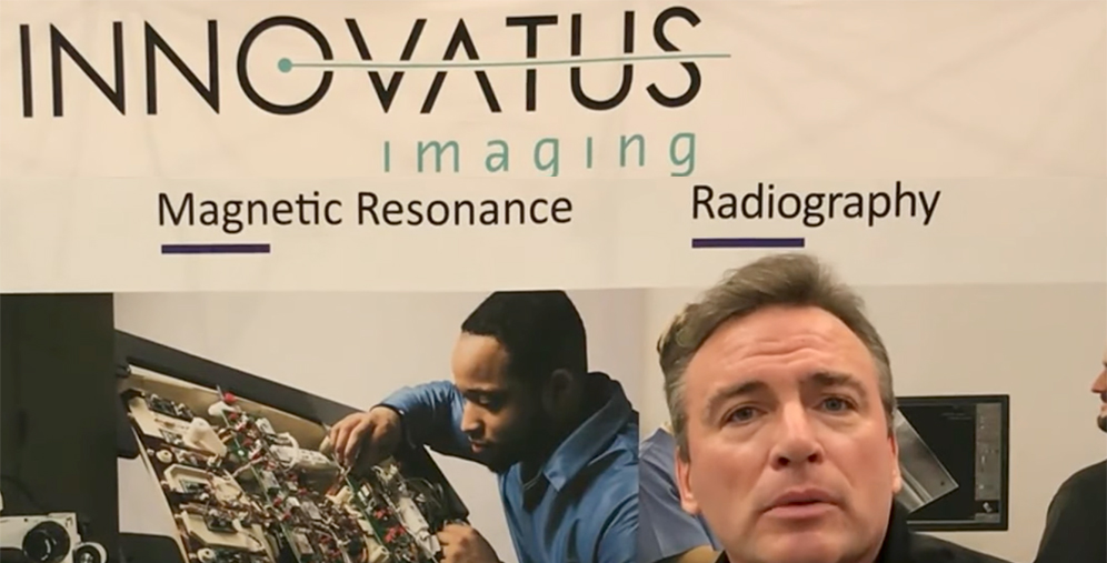 Banner reading 'Innovatus Imaging' with 'Magnetic Resonance' and 'Radiography' sections; man in foreground at a booth.