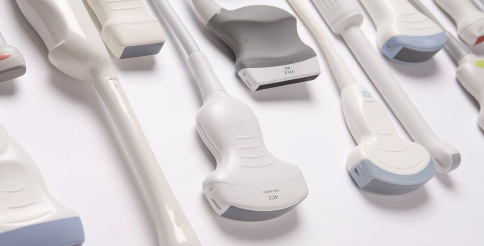 Array of white ultrasound probes laid out on a surface, varied shapes and sizes visible