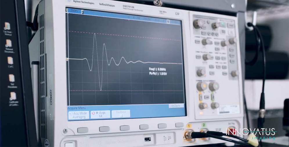 An Agilent InfiniiVision oscilloscope showing a waveform on its screen in a laboratory setting with control knobs on the right side, cables attached to the front panel.