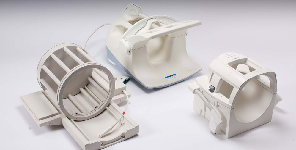 Three white medical imaging device components on a white surface, including a circular gantry ring and two housing units.