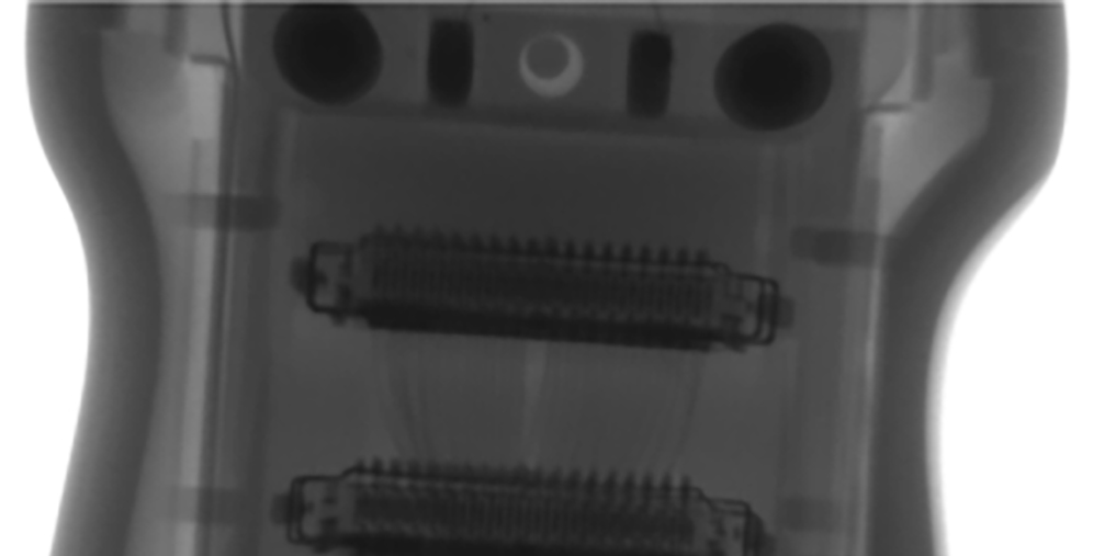 X-ray view of a handheld electronic device showing two parallel ribbon-style connectors and circular ports at the top edge.